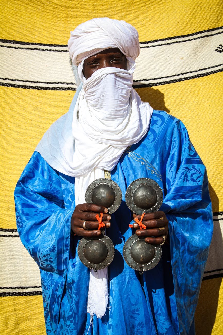 man in traditional clothes holding set of krakeb instruments - touaregs